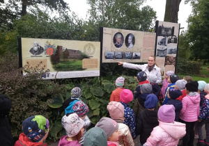 Dyrektor biblioteki opowiada dzieciom historię Opatówka na spacerze w parku