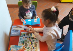 Dzieci przy stoliku oglądają książki